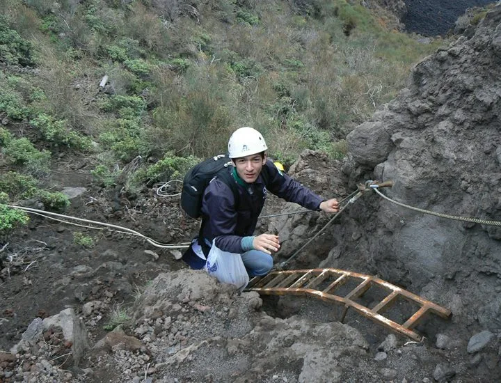 Tecnico in arrampicata con scala su terreno vulcanico